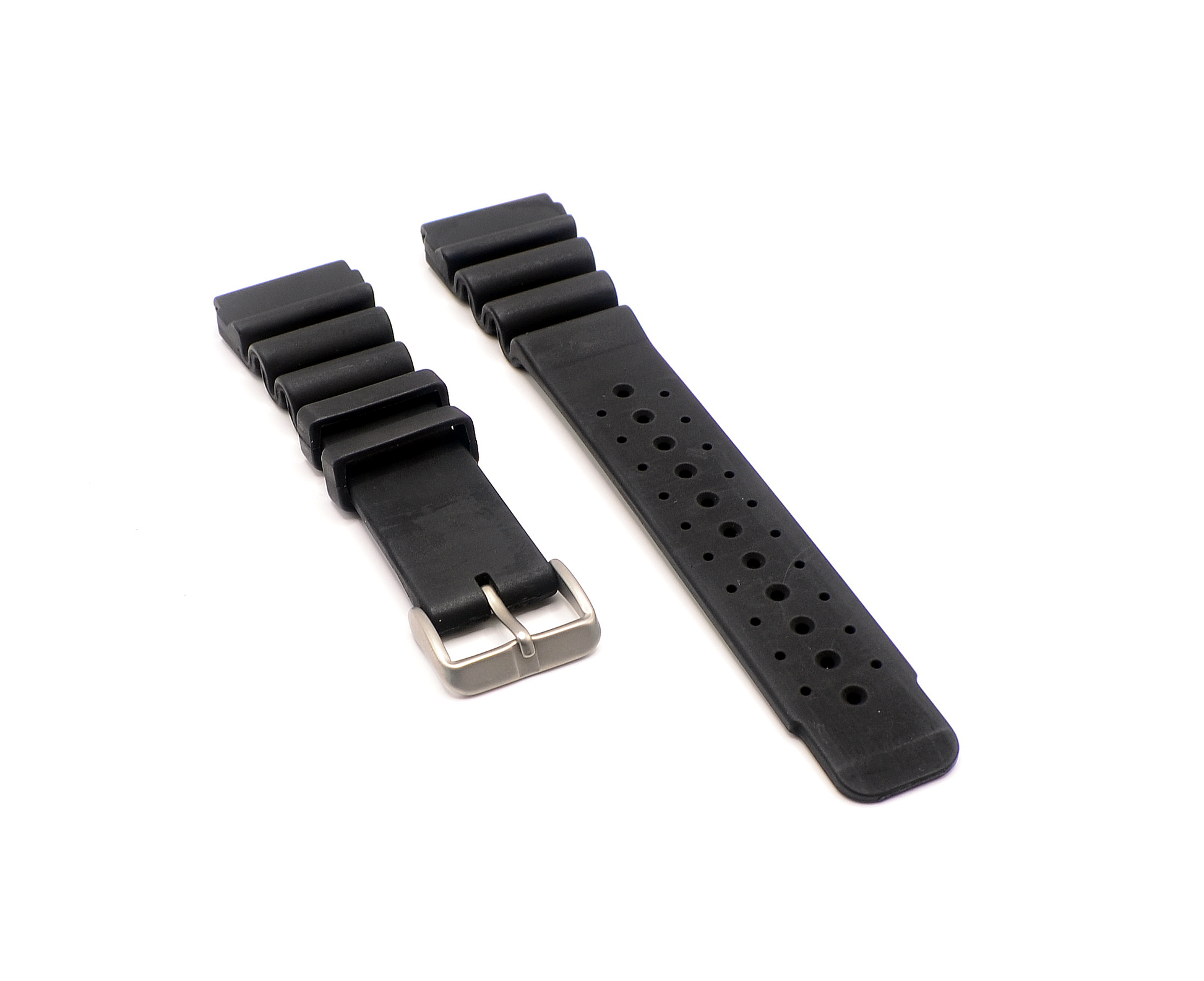 A 24mm black rubber watch strap with a stainless steel buckle, laid flat showing both the long and short pieces. The strap features multiple adjustment holes for a secure fit.