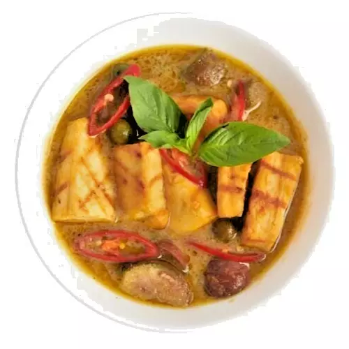 A bowl of green curry with tofu, aubergine, fresh basil, and red chillies made using Nam Jai Green Curry Paste.