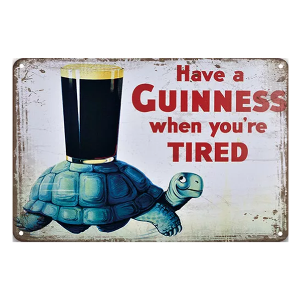 Retro metal sign featuring a cheerful turtle carrying a pint of Guinness and the slogan "Have a Guinness When You’re Tired." Perfect for pubs and home bars.