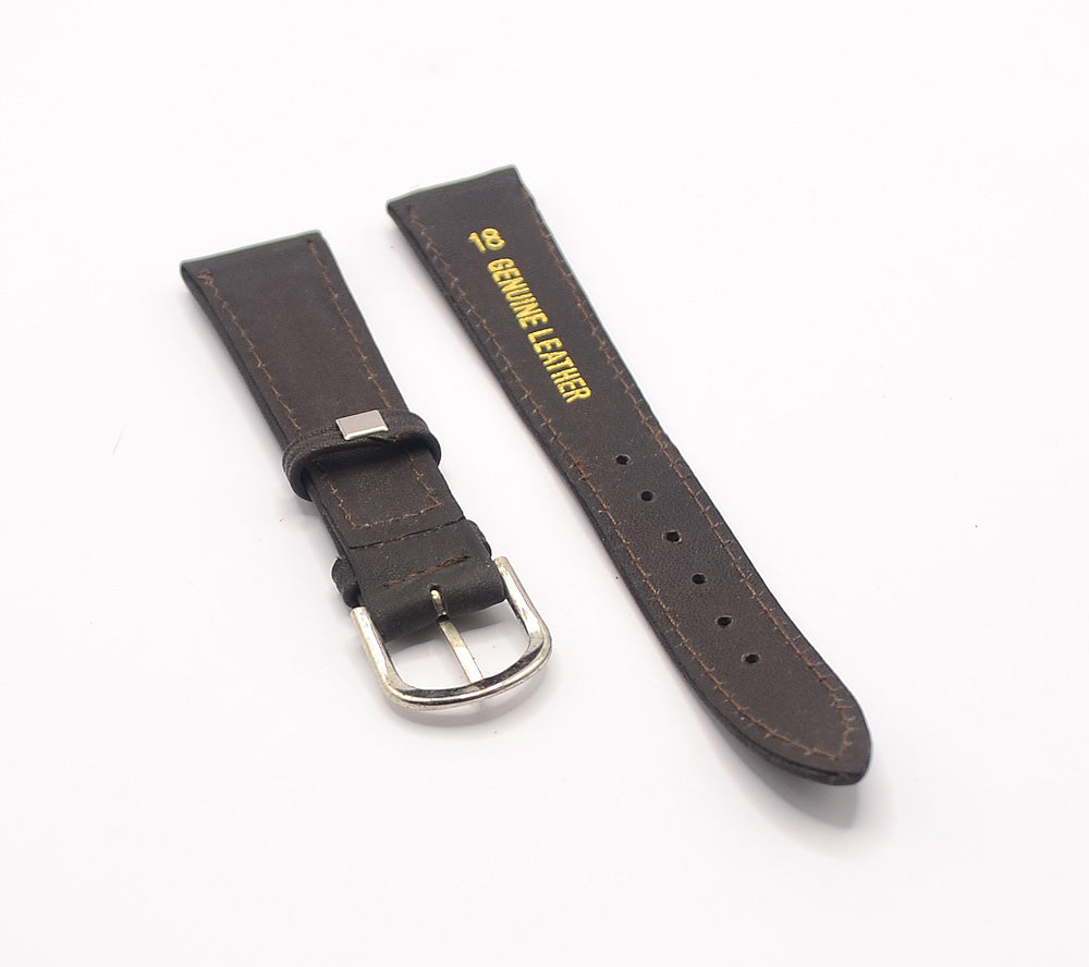 The underside of a brown leather watch strap, with "Genuine Leather" embossed in gold text on the longer piece. The polished silver buckle is visible on the shorter piece.